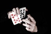 Young magicians hands holding a lot of play cards. black background