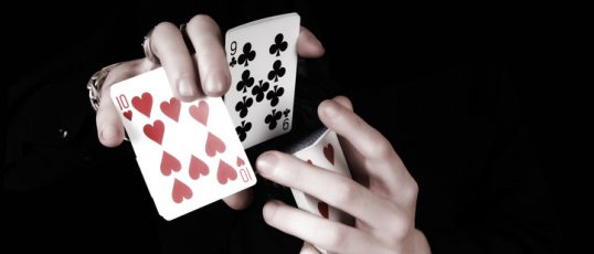 Young magicians hands holding a lot of play cards. black background